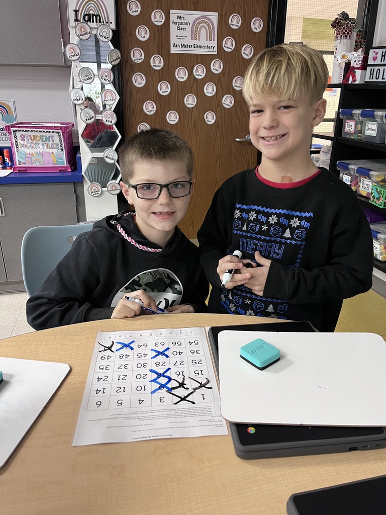 Two students smiling for the camera with their activity on the table in front of them