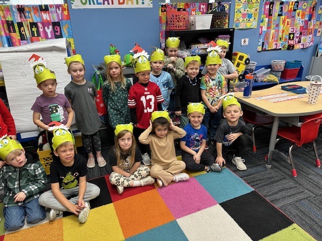 Students with their grinch hats on in a colorful classroom.