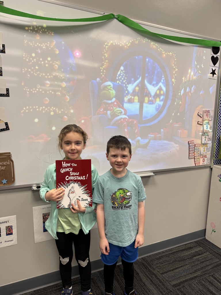Two students standing in front of the white board with a Christmas scene being displayed.
