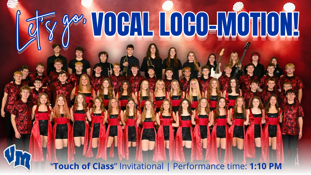 Large group of Van Meter Show Choir performers in coordinated red and black outfits posing on stage under bright lights for the "Touch of Class" invitational.