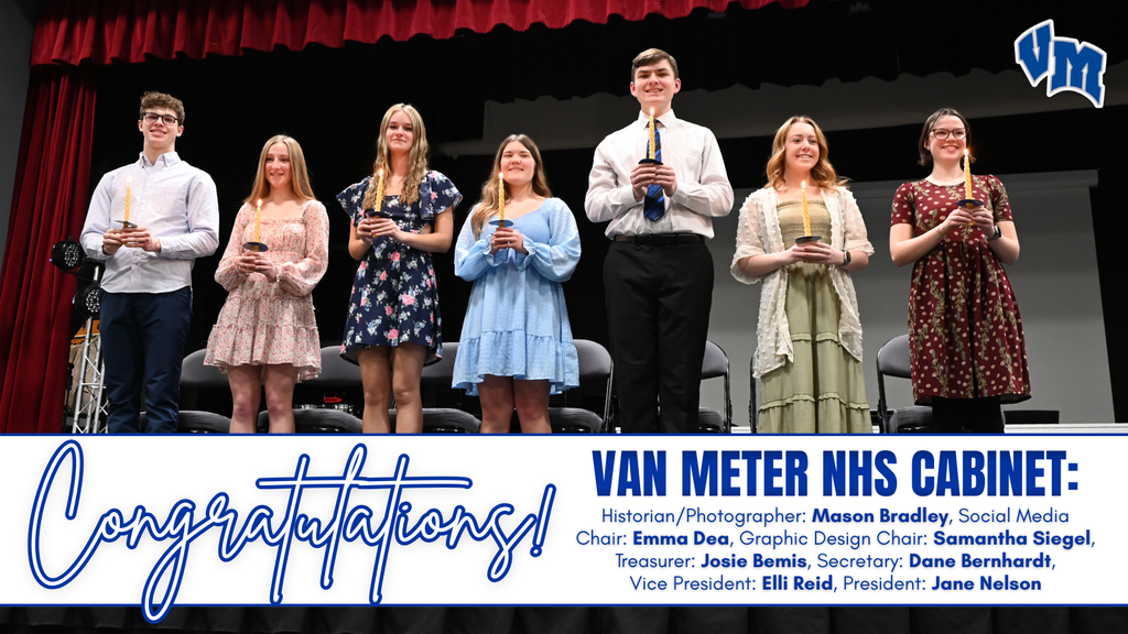 Seven students stand on stage holding candles during a Van Meter NHS Cabinet ceremony with a congratulatory banner below.