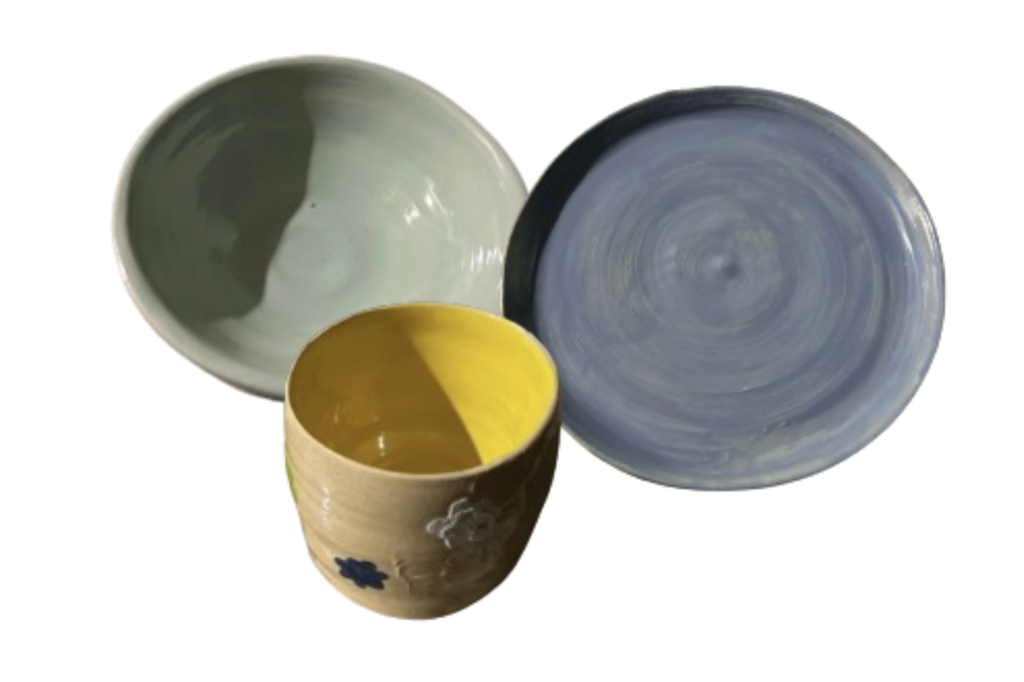 Set of three ceramic dishes including a light green bowl, a blue plate with circular patterns, and a yellow interior cup with floral designs.