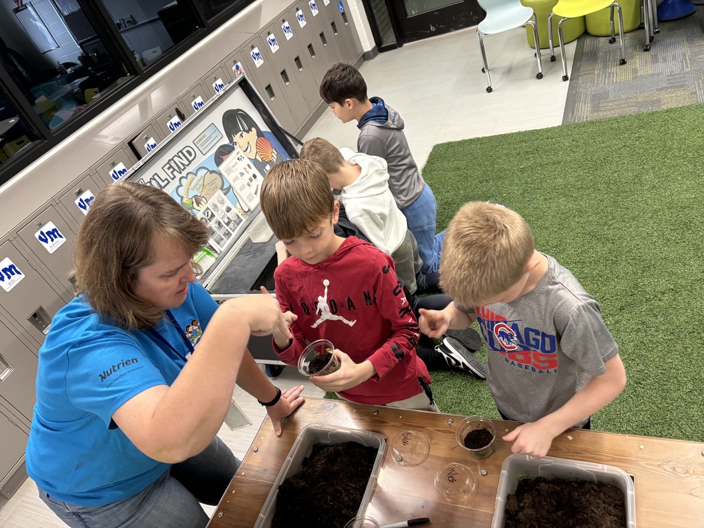 Teacher showing students how to mix the soil around in their individual cups.