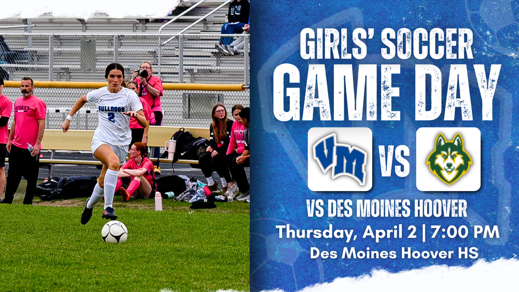 Female soccer player in white uniform dribbling the ball on green field during a game with spectators in the background.