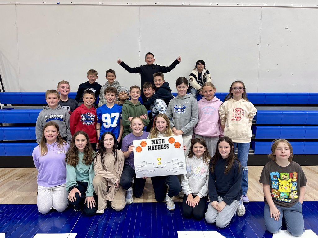 Group of children posing in a gym with a 'Math Madness' poster showing a tournament bracket and trophy illustration.