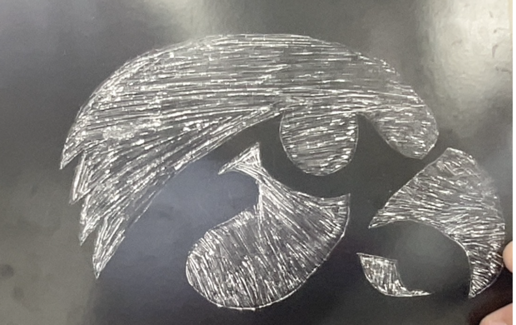 A black surface featuring a stylized hawk head logo in white scratch-like lines, with bold shapes and textured shading.