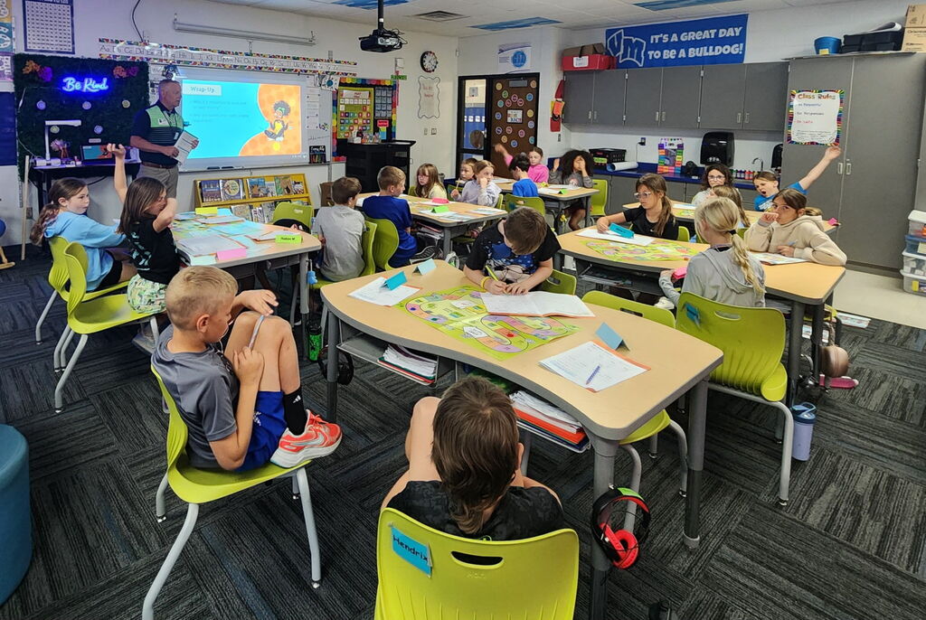Classroom of students participates in a Junior Achievement lesson while a presenter leads discussion at the front of the room.