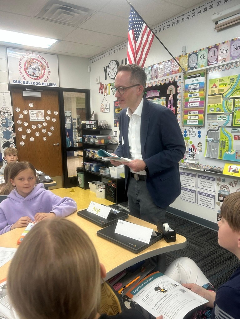 Guest speaker visits elementary classroom, talking with students during a Junior Achievement city-planning lesson.