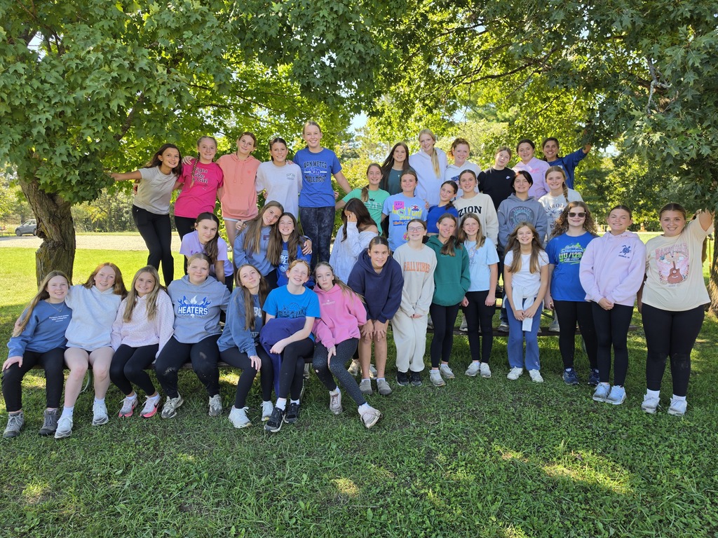 1. Large group of students pose together beneath a leafy shade tree after participating in an outdoor activity.