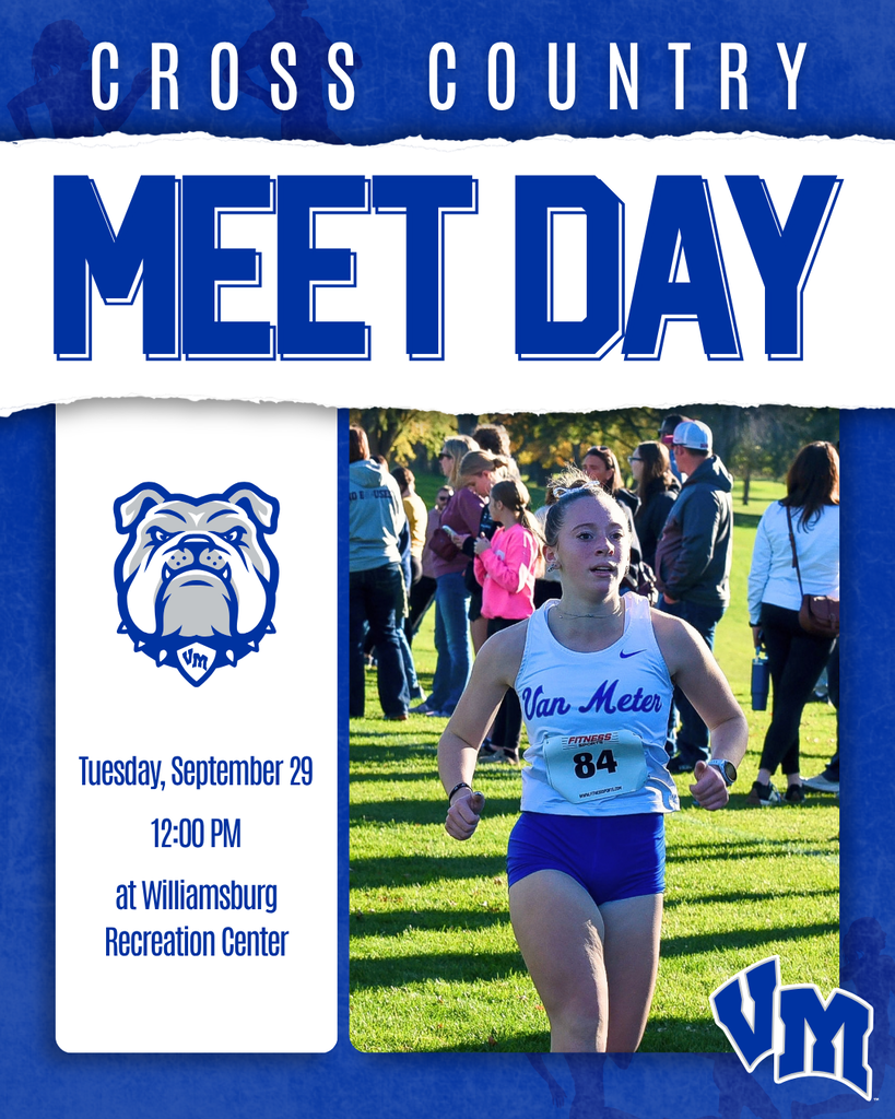 Female cross country runner wearing Van Meter uniform competing in a race with spectators in the background.