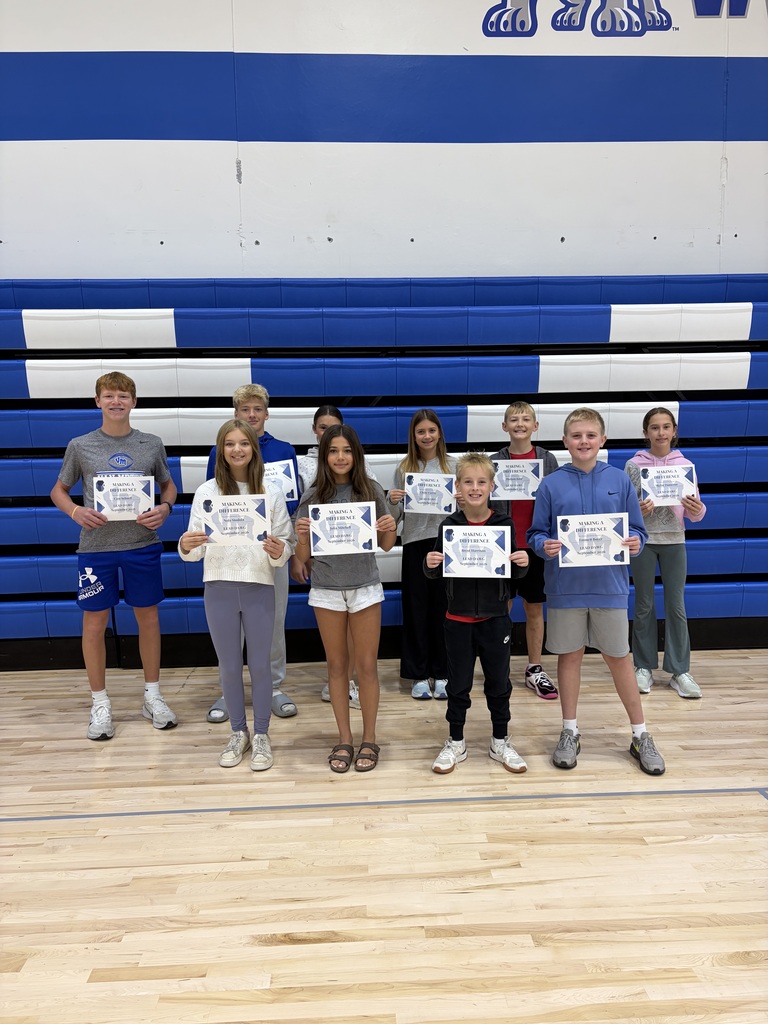 Group of ten smiling students standing in a gym holding certificates of achievement.