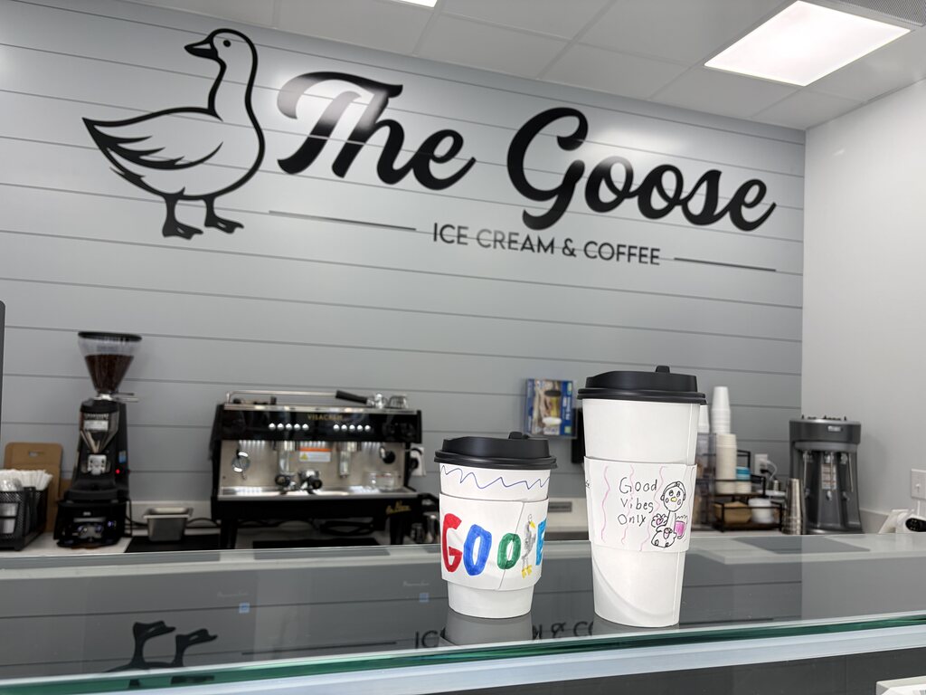 Interior of The Goose ice cream and coffee shop with two decorated takeaway coffee cups on the counter in front of an espresso machine.