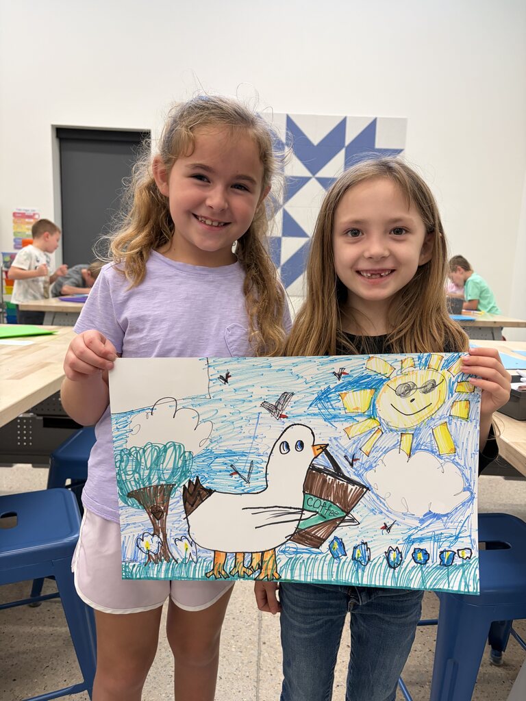 Two young girls proudly display a colorful drawing of a smiling sun, a large white bird, trees, and flowers under a bright blue sky.