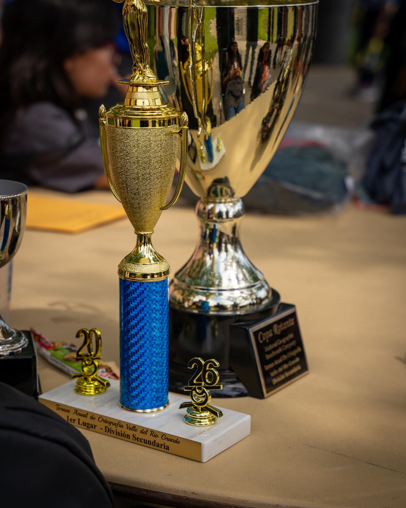 Three trophies on a table. A blue trophy with a number 20, and a silver trophy with a number 26.