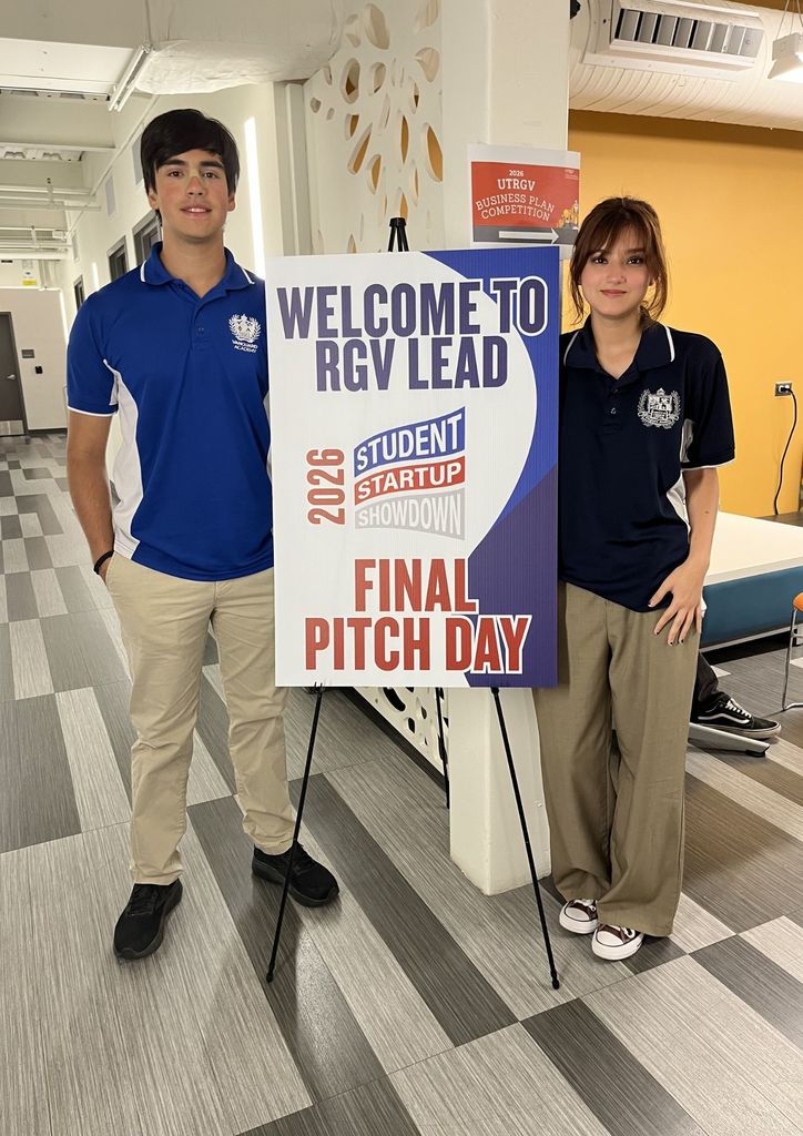 Two individuals in blue shirts and khaki pants stand behind a sign reading "Welcome to RGV Lead 2026 Startup Showdown Final Pitch Day."