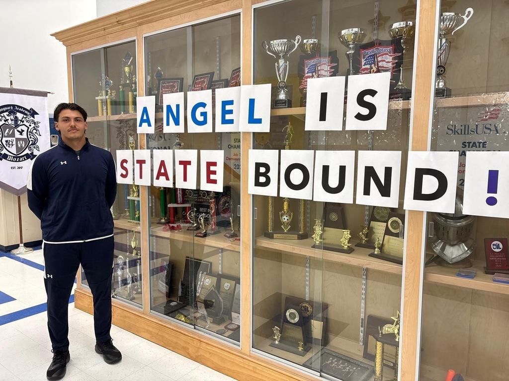 A man stands in front of a glass display case filled with trophies, with the text "ANGEL IS STATE BOUND!" above.