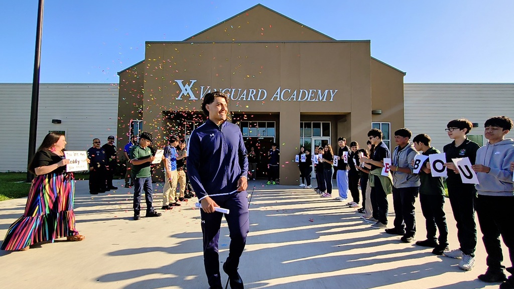People line up outside a building, "XGuard Academy" on the wall. A person in blue walks toward them.