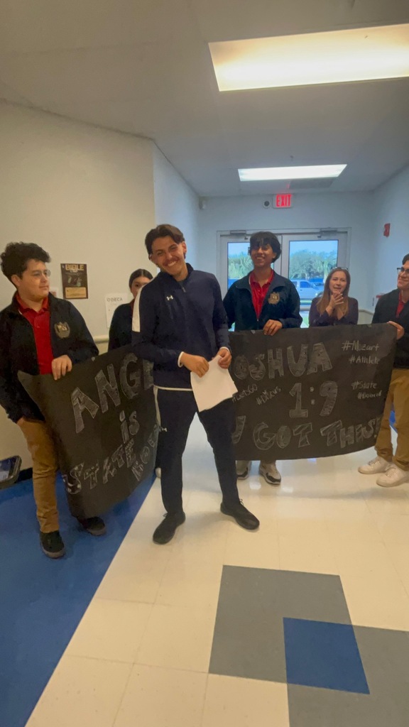 Group of people in a hallway with a banner held by two individuals. The banner reads "ANGEL is."