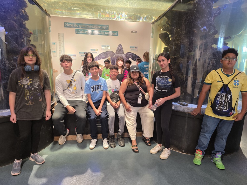 A group of people pose for a photo in a room with a large aquarium in the background.