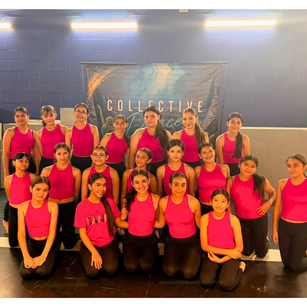 A group of women in pink tops and black leggings poses for a photo in a studio.