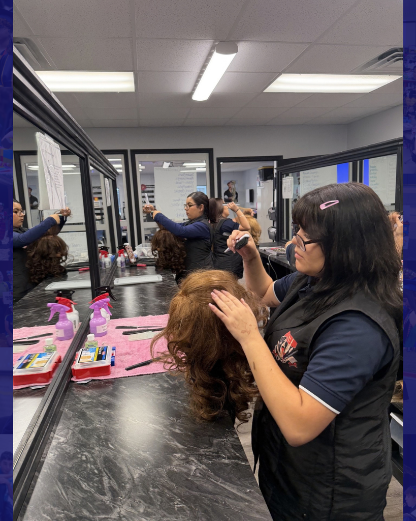 Woman with dark hair styling a wig in a beauty salon. Bright overhead lighting and mirrors.