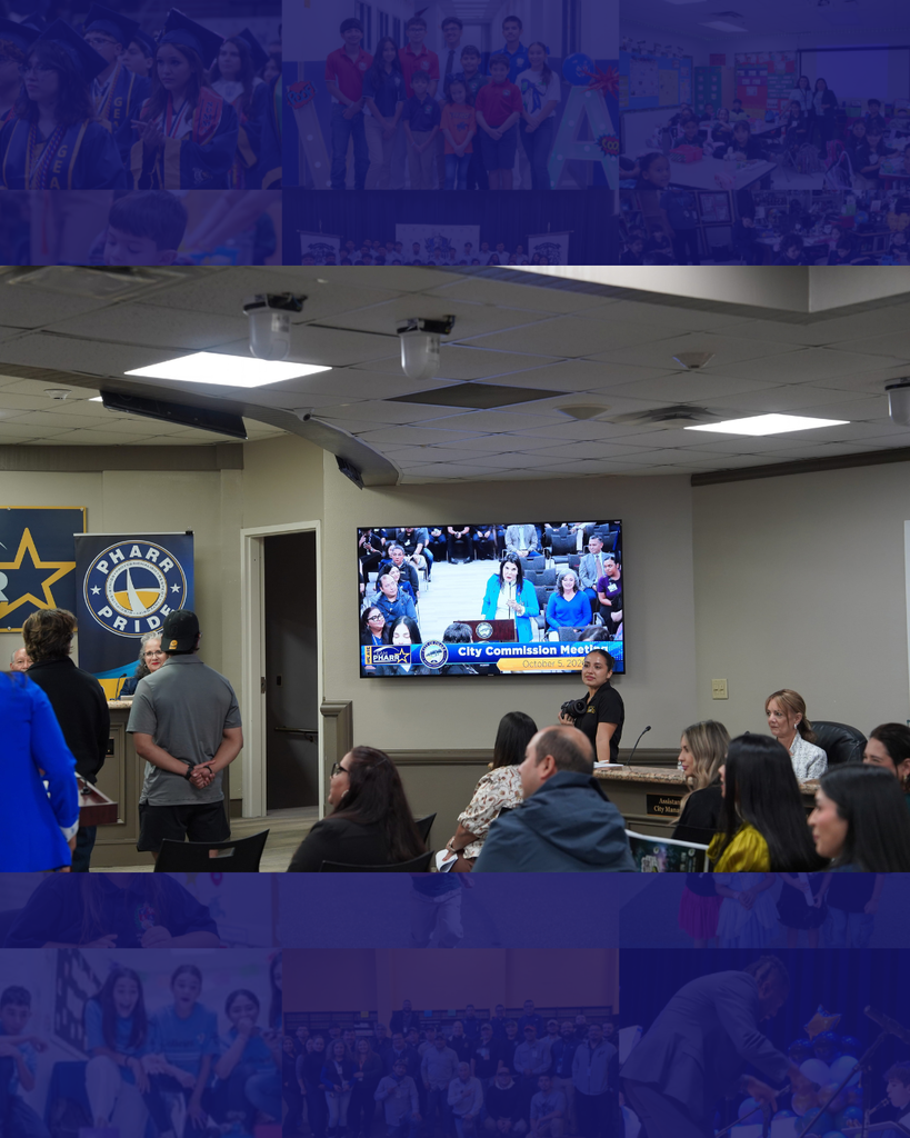 A meeting in a conference room with multiple people sitting. A monitor is mounted on the wall.