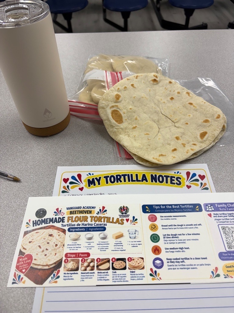 A table with a tortilla, a cup, and a recipe guide. The guide is titled "My Tortilla Notes."