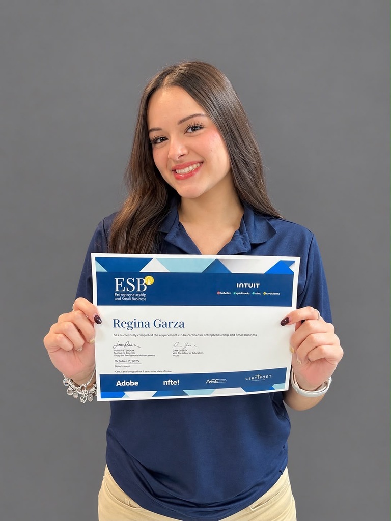 A woman in a blue shirt holds a certificate with "ESB" at the top, smiling.
