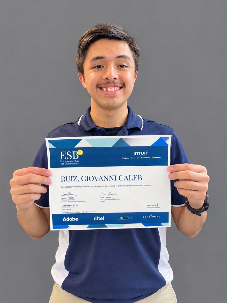Man in blue and white polo holds certificate for Ruiz, Giovanni Caleb. Certificate features blue and white design with text and logos.