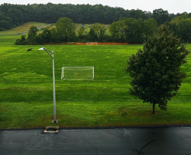 Rainy and wet soccer field with lamp post in the foreground