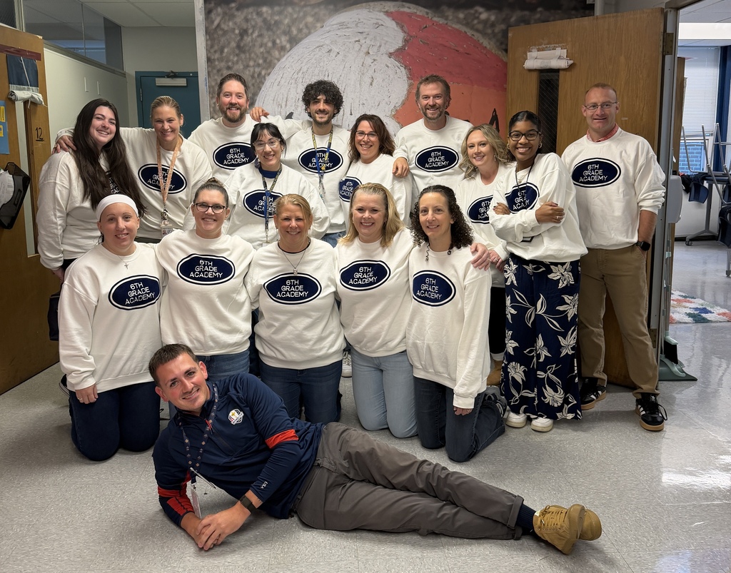 Group photo with 16 individuals wearing the same shirts, except one wear a different shirt