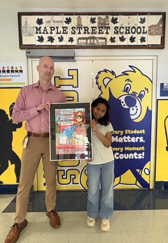Jamie Fernandez stands holding her poster with Maple Street School Principal Josh Egan