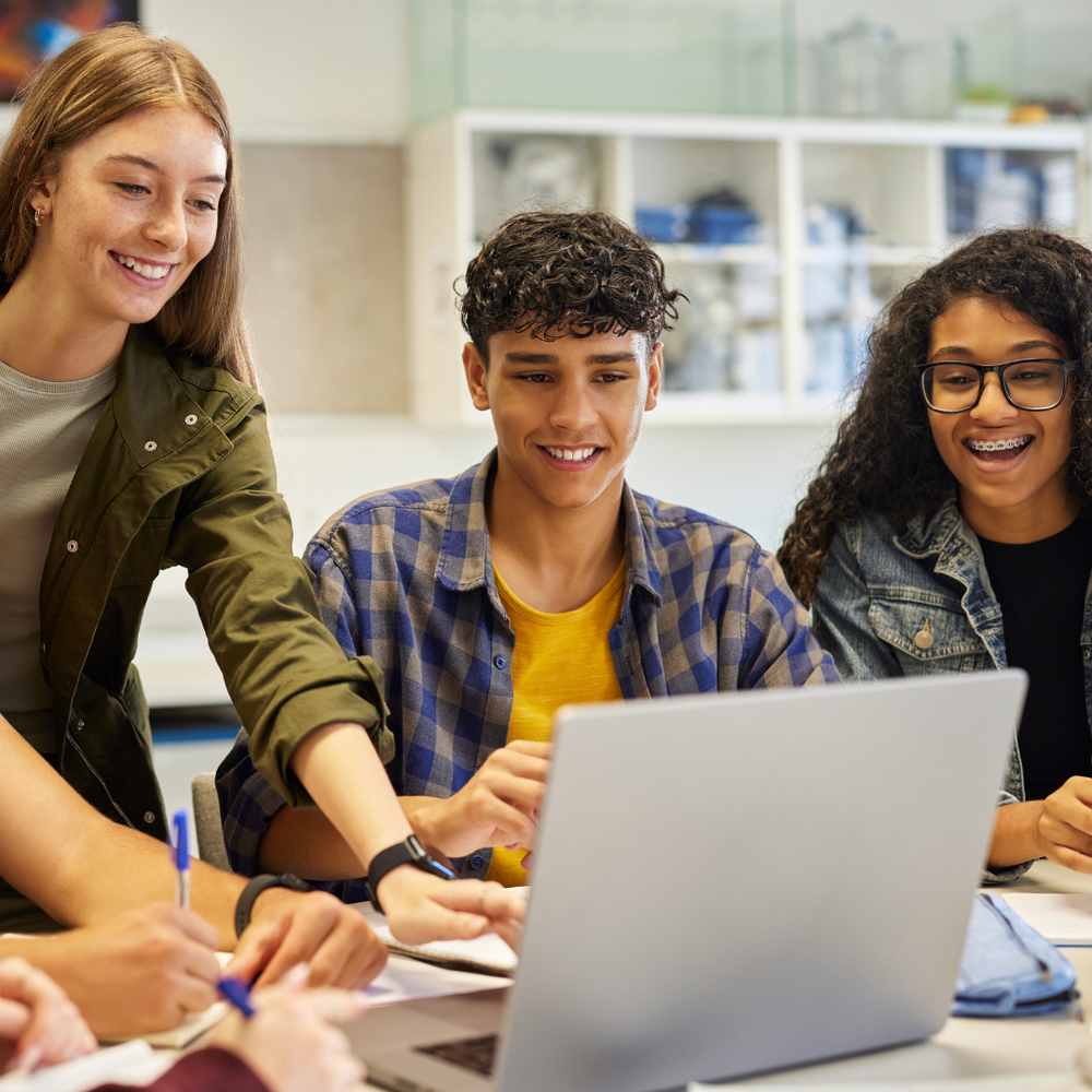 3 students looking at a laptop together