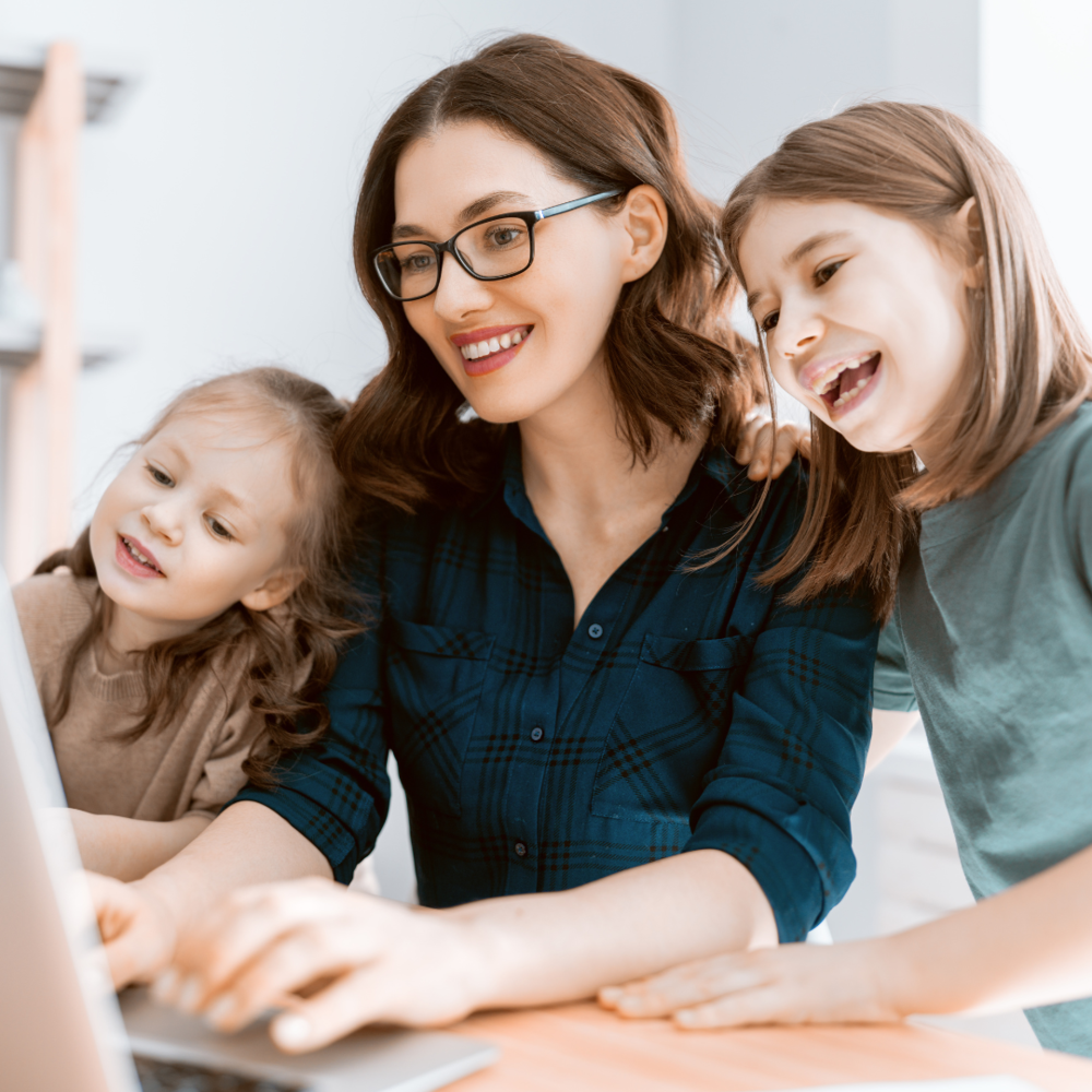 Mother with her two daughters smiling while working on a laptop