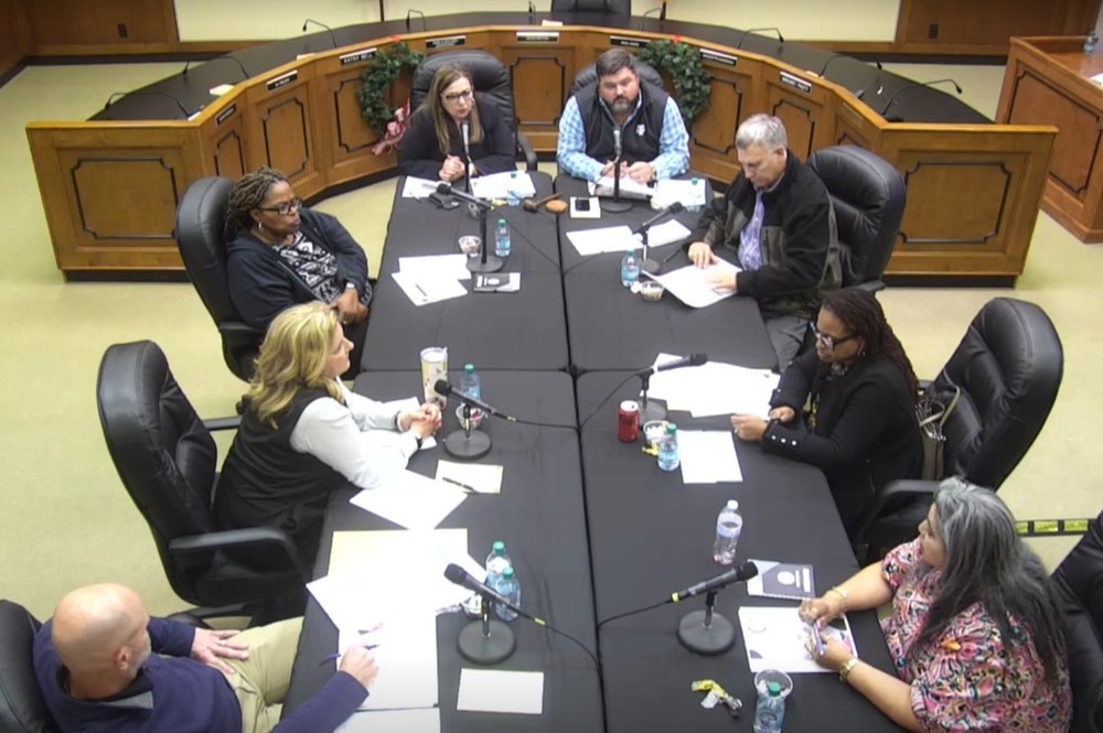 8 board members around a table talking