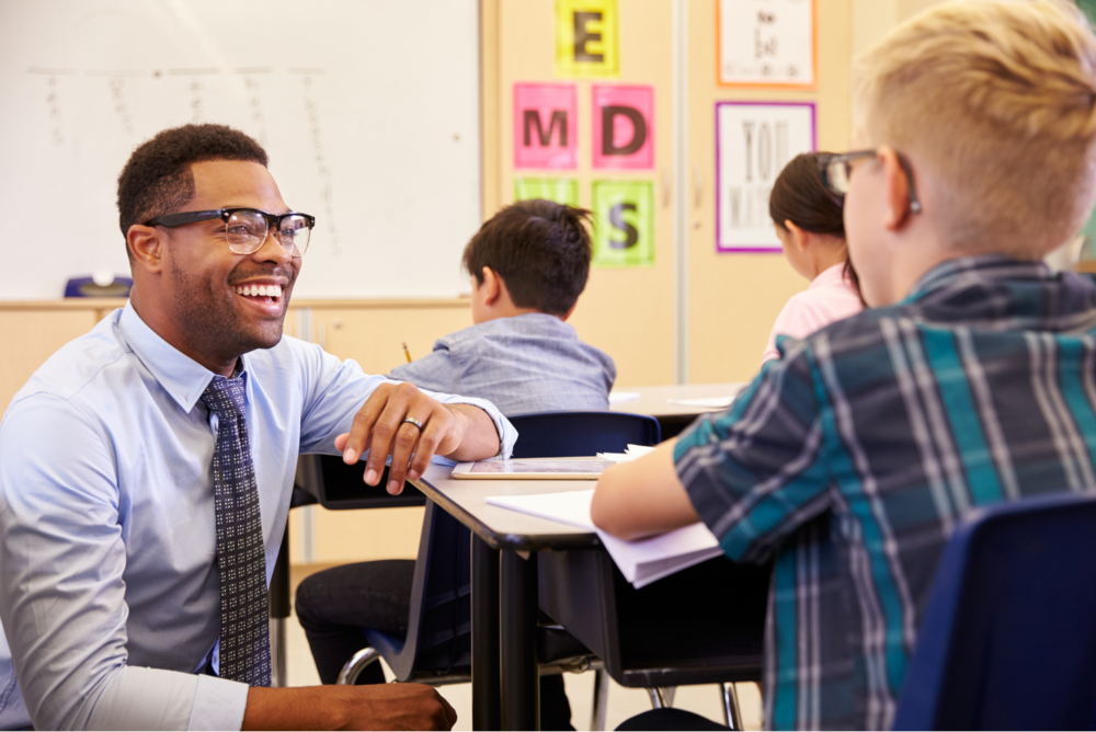 teacher talking with student at desk