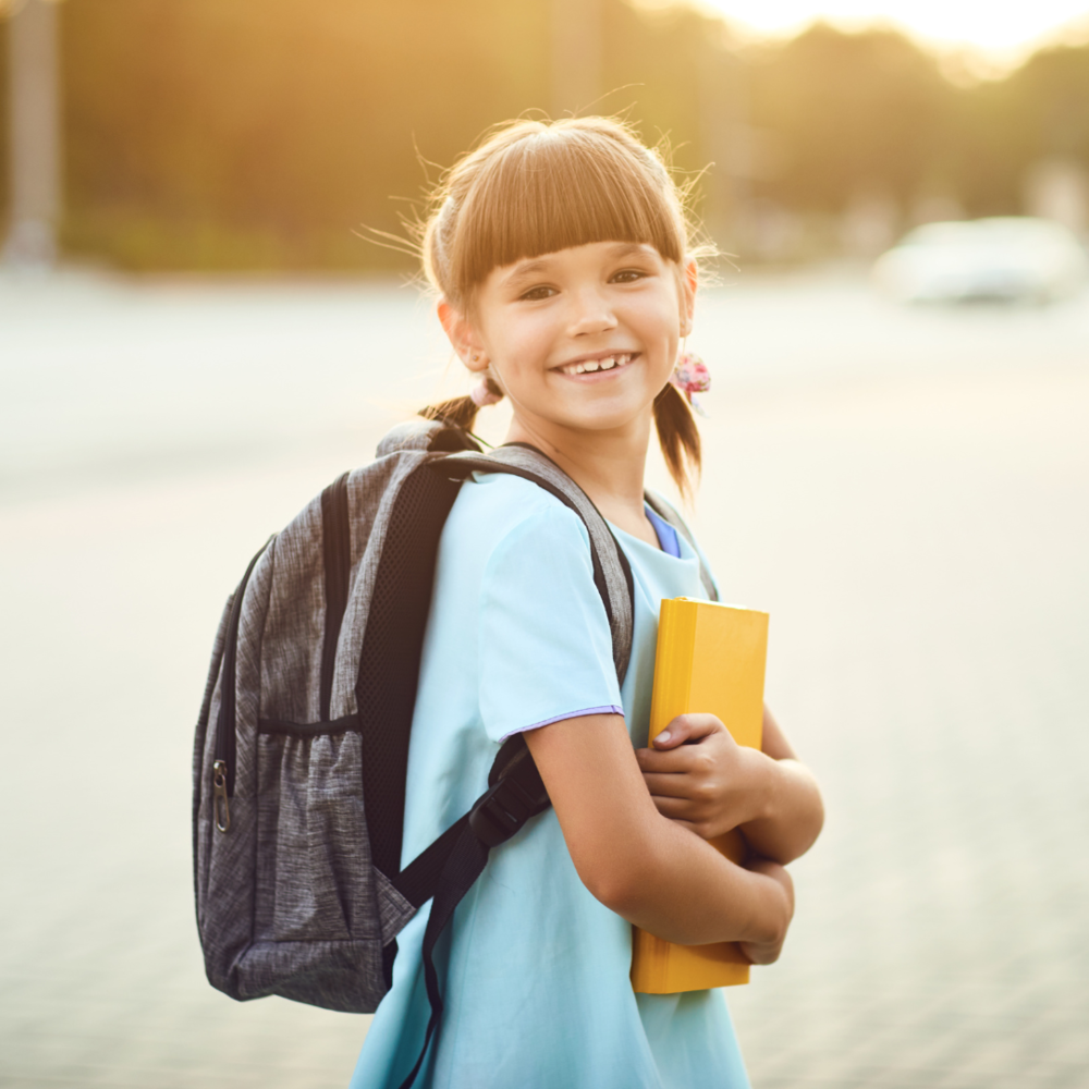 Image of female student with backpack and book smiling