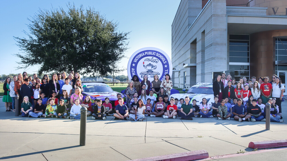Teachers and students in front of race cars and VISD inflatable