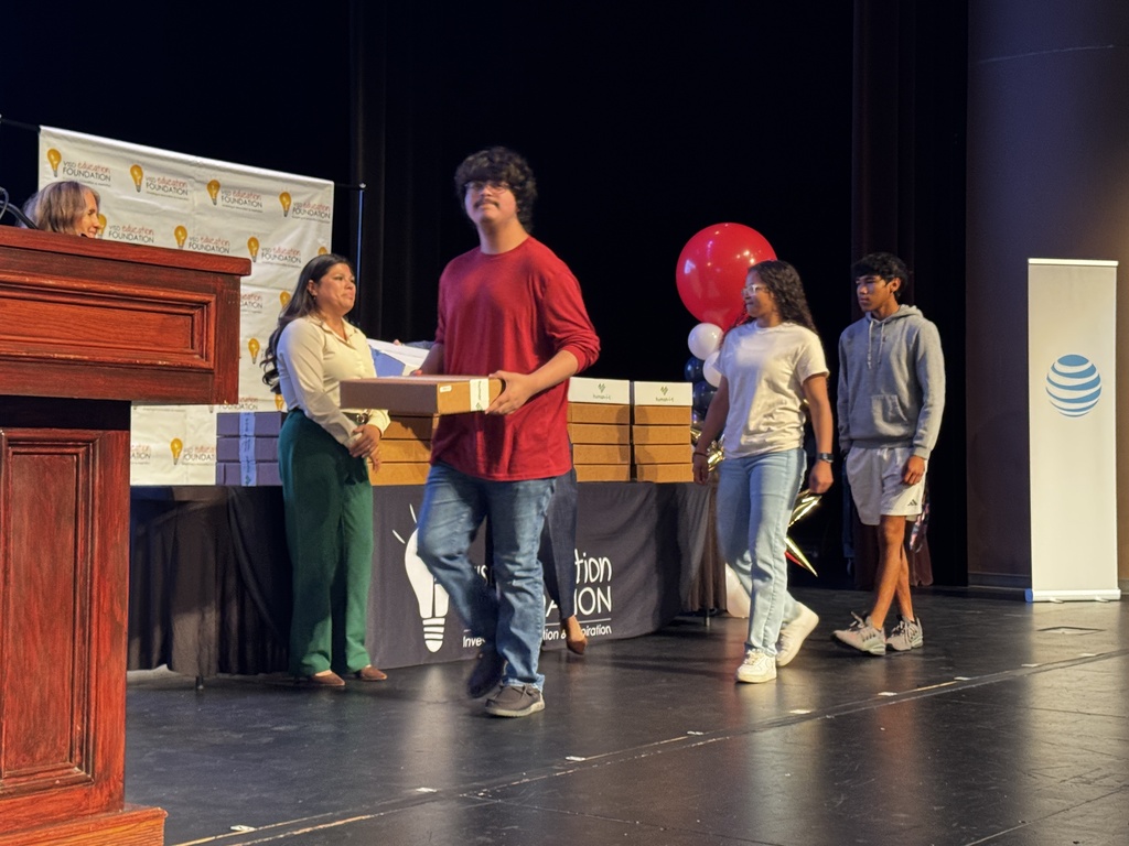 Students walking forward to receive their new laptops during the July 9 distribution event.