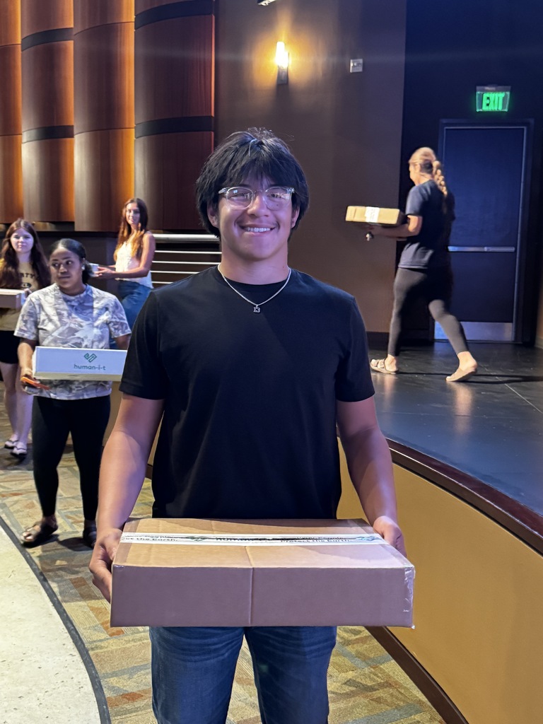 Victoria student smiling while holding refurbished laptop donated through AT&T and Human-I-.
