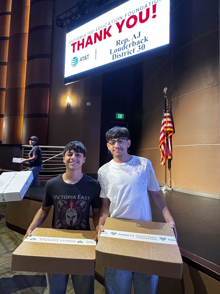 Two Victoria students smile while holding refurbished laptops donated through AT&T and Human-I-.