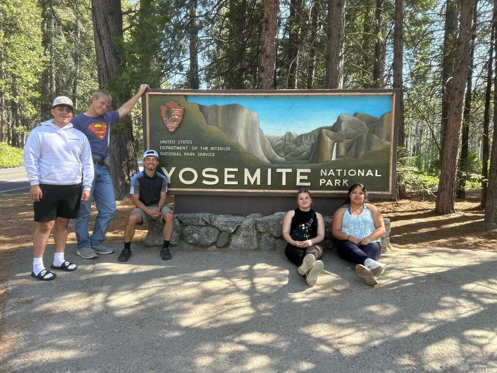 Seniors posing in front of the Yosemite National Park sign.