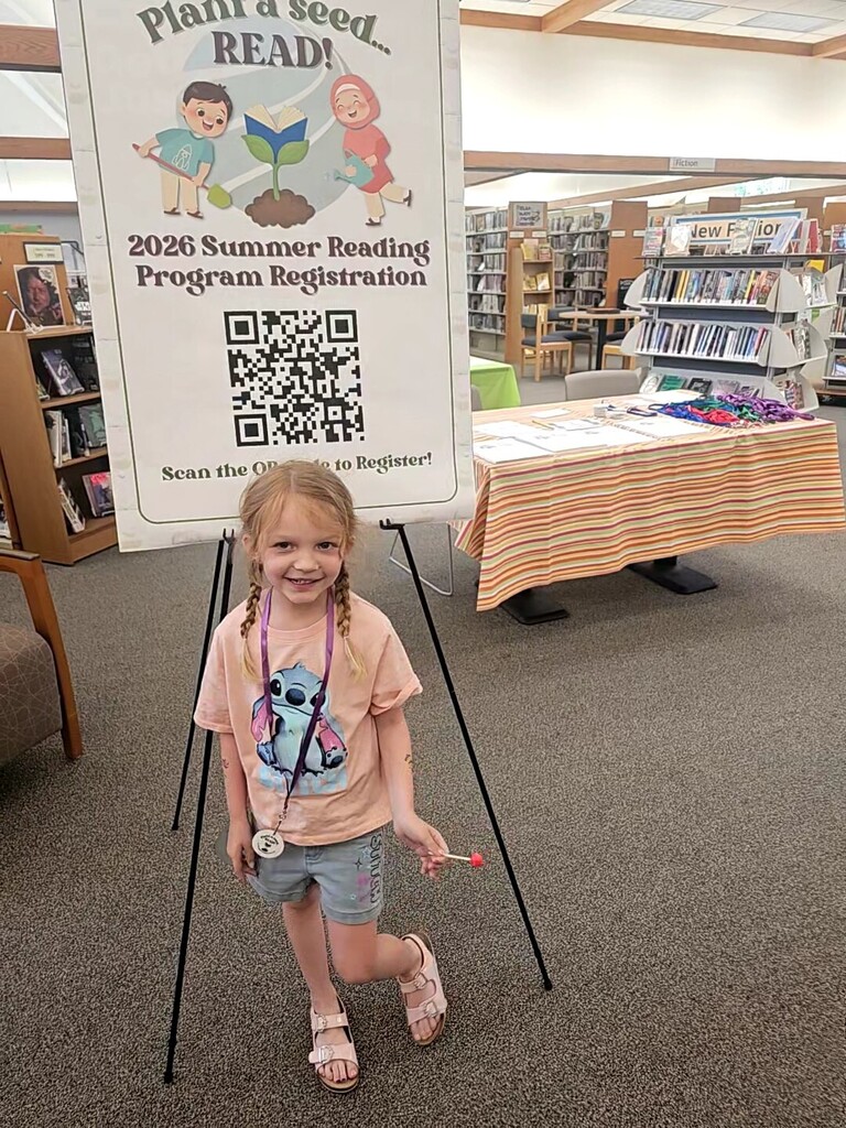 Young girl standing by Summer Reading registration sign