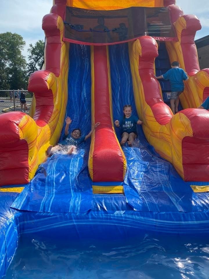 Two students going down inflatable waterslide