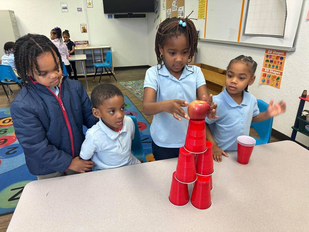 kids stacking cups with apple on top
