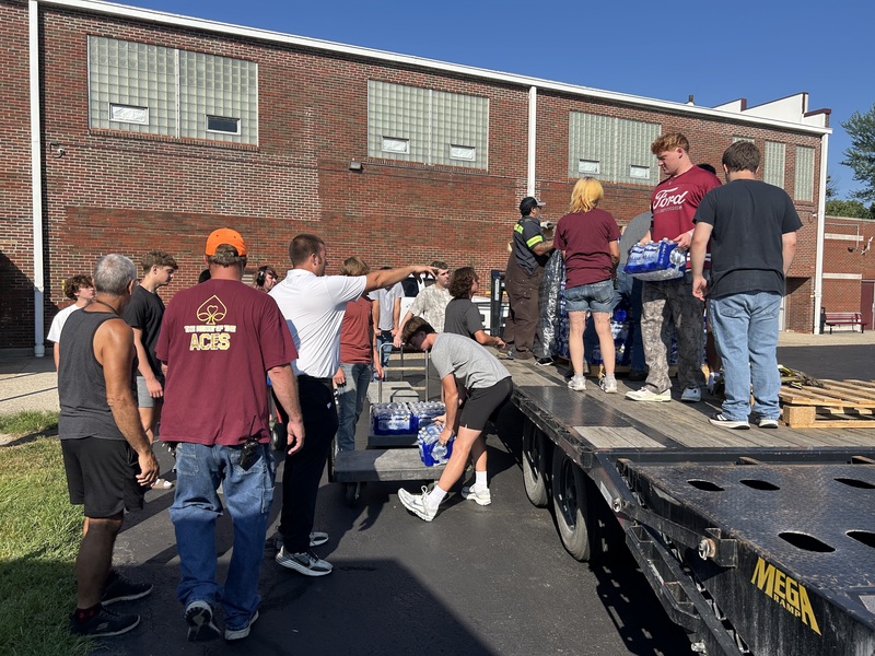 Students, Custodians, Principal unloading water