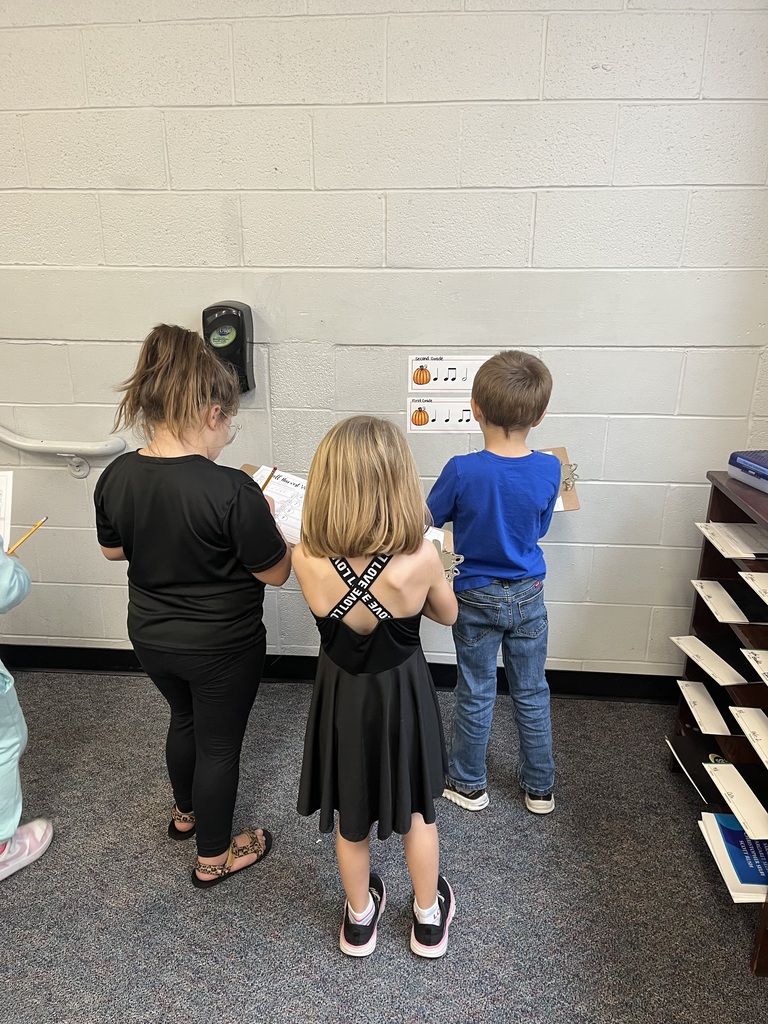 Students standing in front of the wall with clipboards.