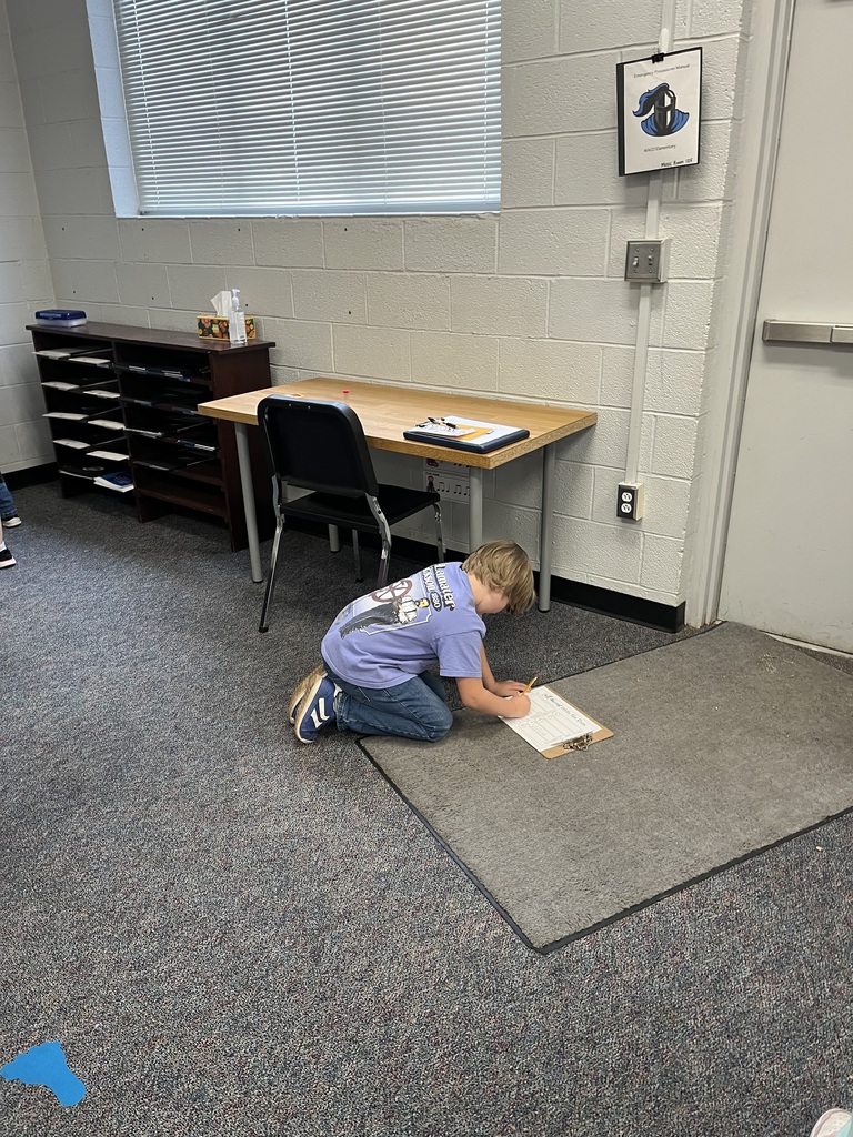 Student kneeling on the ground with a clipboard.