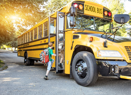 a young boy stepping onto a yellow school bus