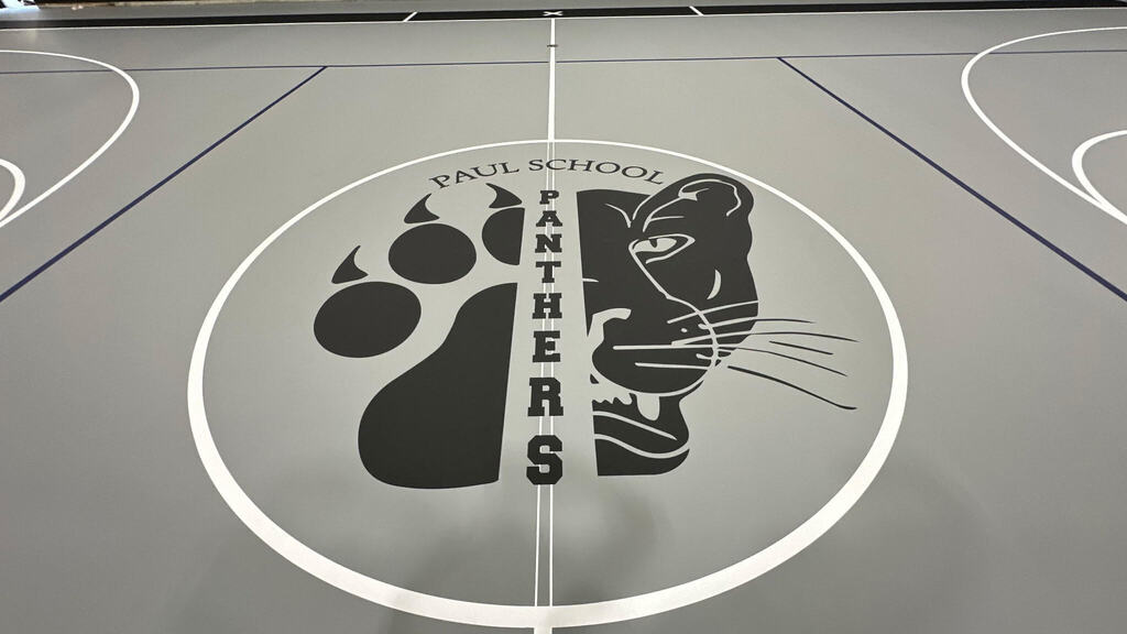 graphics of our new gym floor with the half face of a panther and the other half of a paw. It is a grey floor with white and royal blue lines